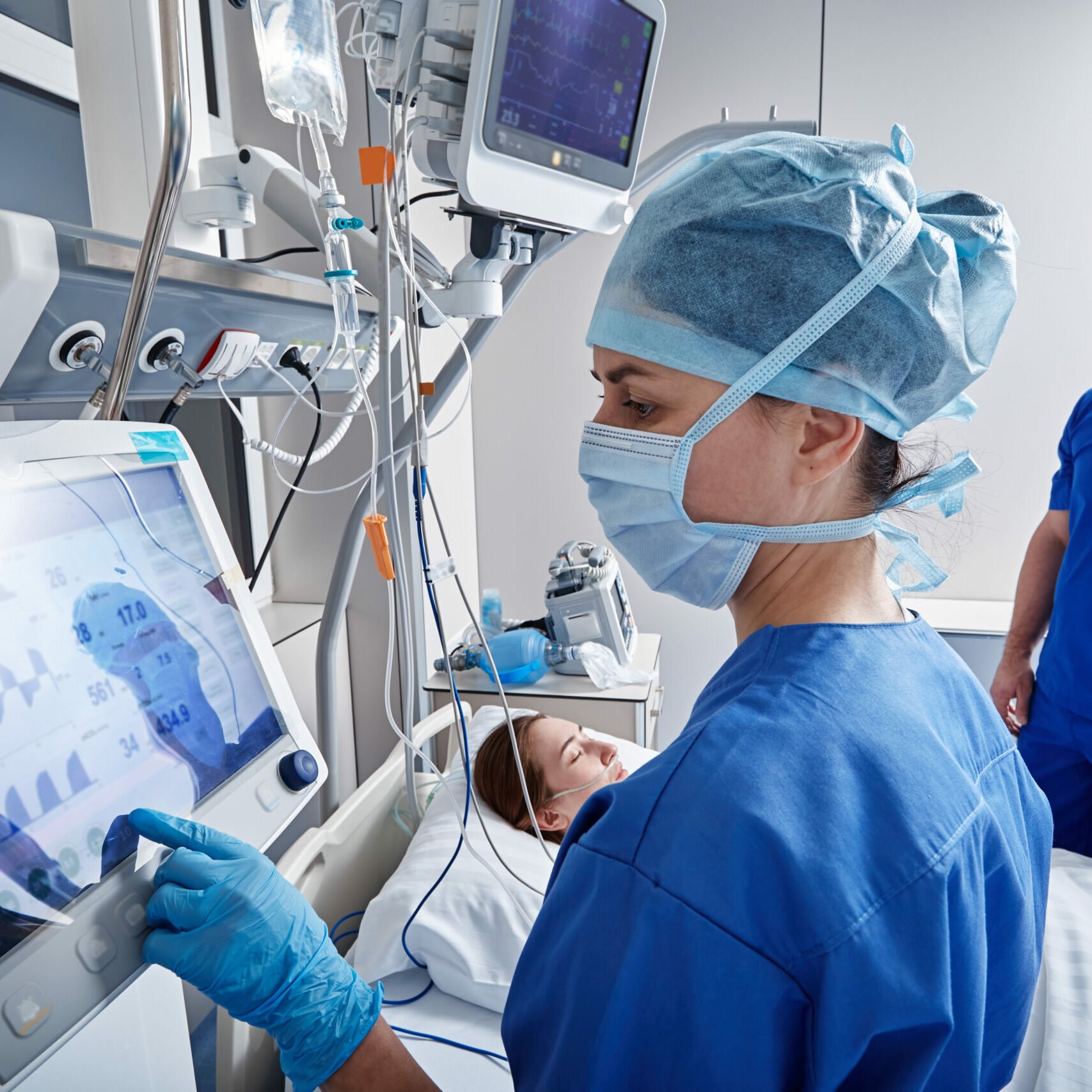 Hospital nurses checking on woman patient at intensive care unit and monitoring her health with medical equipment and sensors. ICU